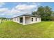 Single story home with green backyard and sliding glass doors to the patio at 4780 Sw 129Th Pl, Ocala, FL 34473