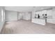 Spacious living area with gray flooring, leading into kitchen with white cabinets and stainless appliances at 4780 Sw 129Th Pl, Ocala, FL 34473