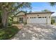 Inviting home featuring a two-car garage and a manicured lawn with stone paved driveway at 489 Penny Ln, Maitland, FL 32751