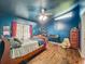 Cozy bedroom with dark blue walls, wooden floors, a ceiling fan and a red curtained window at 4942 Eden View Ct, Orlando, FL 32810