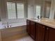 Bright bathroom features a double sink vanity and a large soaking tub with plantation shutters at 541 Arena Dr, Davenport, FL 33837