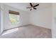 A bright carpeted bedroom featuring a ceiling fan and window at 5500 Metrowest Blvd # 203, Orlando, FL 32811