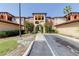 Beautiful condo with terra cotta tile roof, beige stucco, and lush tropical landscaping at 5500 Metrowest Blvd # 203, Orlando, FL 32811