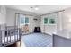 Sweet Bedroom has a gray crib, blue rug and lots of natural light with two windows at 609 Langholm Dr, Winter Park, FL 32789