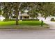 Inviting home with a lush green lawn, trimmed hedges, and a large shade tree in a tranquil setting at 609 Langholm Dr, Winter Park, FL 32789