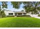 Charming single-story home with a well-manicured lawn, mature trees, and a welcoming blue front door at 609 Langholm Dr, Winter Park, FL 32789