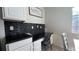 Desk area with modern black backsplash, black countertop, white cabinets and seating area at 720 Las Fuentes Dr, Kissimmee, FL 34746