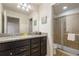 Bathroom with granite countertop, dual sinks, dark wood cabinets and glass enclosed shower at 8801 Macapa Dr, Kissimmee, FL 34747