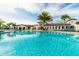 Serene community pool with clear blue water, palm trees, lounge chairs, and a resort-style building at 8801 Macapa Dr, Kissimmee, FL 34747