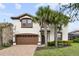 Beautiful two-story home with a well-maintained lawn, mature landscaping, and a brick driveway at 8801 Macapa Dr, Kissimmee, FL 34747