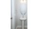 A neutral-toned bathroom has a pedestal sink and round mirror above wood-look flooring at 922 Wild Date Ln, Lake Mary, FL 32746