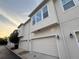 Exterior garage-level view of townhomes with white stucco and carriage-style garage doors at 922 Wild Date Ln, Lake Mary, FL 32746