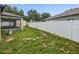 Backyard view with white fence, lanai, and green lawn at 112 Lake Butler Ave, Haines City, FL 33844