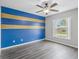 A bedroom with blue and gold accent wall, ceiling fan, hard surface floors, and a window at 112 Lake Butler Ave, Haines City, FL 33844