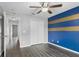 A bedroom with hard surface floors, a closet, ceiling fan, blue and gold accent wall, and white trim at 112 Lake Butler Ave, Haines City, FL 33844