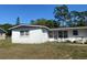 View of a one-story home with white cinderblock and a dark roof, with mature trees on the property at 115 Lake Dot Dr, Sanford, FL 32773
