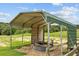 Animal shelter in the pasture with a round hay feeder and wooden fence at 12434 Sullivan Rd, Clermont, FL 34715