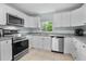Well-lit kitchen boasts stainless steel appliances, white cabinets, and practical layout at 12434 Sullivan Rd, Clermont, FL 34715