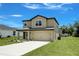 Two-story home with tan siding, a covered front entry and two-car garage at 1303 Congo Ct, Kissimmee, FL 34759