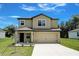 Two-story home featuring a beige exterior, attached two-car garage, and well-maintained front lawn at 1303 Congo Ct, Kissimmee, FL 34759