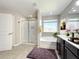 Bright bathroom featuring a vanity, soaking tub, and glass enclosed shower with marble look tile at 137 Drayton Ave, Davenport, FL 33837