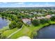 An aerial view highlights a lakeside home with lush greenery, mature trees, and a pathway leading to a sandy beach at 14038 Bluebird Park Rd, Windermere, FL 34786