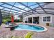 A beautiful screened-in pool and spa are surrounded by a brick patio and lush greenery, perfect for outdoor relaxation at 14038 Bluebird Park Rd, Windermere, FL 34786