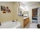 Bright bathroom with a soaking tub, light wood cabinets, double sinks, and a doorway leading to the bedroom at 149 Spanish Bay Dr, Sanford, FL 32771