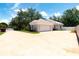 Wide angle view of light colored home with large driveway, manicured bushes and mature trees under blue skies at 1586 Antoinette Ct, Oviedo, FL 32765