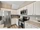 Spacious kitchen with stainless steel appliances, sleek white cabinets, and stone countertops at 17516 Blessing Dr, Clermont, FL 34714
