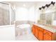 Luxurious bathroom with a soaking tub, glass-enclosed shower, and vanity with granite countertop, perfect for relaxation at 2404 Bella Vista Dr, Davenport, FL 33897