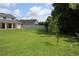 Green back yard with the home on the left and green trees on the right at 2543 Chapala Dr, Kissimmee, FL 34746