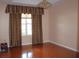 Bedroom featuring a bright window with stylish curtains, a wooden floor, and modern lighting at 2543 Chapala Dr, Kissimmee, FL 34746