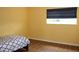 Bright bedroom featuring wood-look floors, yellow walls and a window with dark shades at 2543 Chapala Dr, Kissimmee, FL 34746
