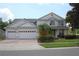 Stunning two-story home with a three-car garage, paver driveway, manicured lawn, and lush landscaping at 2543 Chapala Dr, Kissimmee, FL 34746