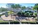 Community playground with a swing set, slides, and seating areas surrounded by trees and shrubs at 2543 Chapala Dr, Kissimmee, FL 34746