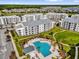 Aerial view of modern apartments around a pool area with palm trees and community green space, offering a resort-like atmosphere at 3180 Paradox Cir # 304, Kissimmee, FL 34746