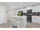 Modern kitchen featuring sleek white cabinets, black appliances, a center island with seating, and stylish tile flooring at 3180 Paradox Cir # 304, Kissimmee, FL 34746