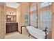 Classic bathroom featuring a soaking tub, glass block shower, dark wood vanity, and abundant natural light at 3461 Michigan St, Lake Mary, FL 32746