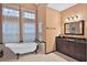 The main bathroom features tile floors and walls and a clawfoot tub beneath a large window at 3461 Michigan St, Lake Mary, FL 32746