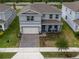 Aerial view of a two-story home with a brick driveway and two rocking chairs on the front porch at 4007 Meandering Bay Dr, Apopka, FL 32712