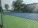Well-maintained tennis court surrounded by lush greenery and a chain-link fence at 5116 Conroy Rd # 411, Orlando, FL 32811