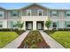 Charming townhome featuring a landscaped walkway leading to the front door with teal shutters and gray siding at 720 Gardenia Ln, Davenport, FL 33897