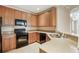 Cozy kitchen featuring granite countertops, wood cabinetry, and black appliances at 8168 Boat Hook Loop # 201/718, Windermere, FL 34786
