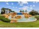 Beautiful rock water fountain with palm trees, lush landscaping, and a clear blue sky at 9844 Beach Port Dr, Winter Garden, FL 34787