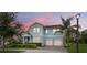 Charming two-story home features a well-manicured lawn, two-car garage, and inviting light blue color at dusk at 9844 Beach Port Dr, Winter Garden, FL 34787