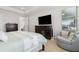Main bedroom with a television, tray ceilings, and a cozy chair positioned beneath a large window at 9844 Beach Port Dr, Winter Garden, FL 34787
