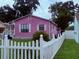 Charming pink home with a white picket fence and well-manicured lawn and mature trees at 1038 26Th St, Orlando, FL 32805