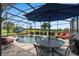 Inviting screened-in pool area features a table, lounge chairs, and well-manicured landscaping at 1212 Zeek Ridge St, Clermont, FL 34715