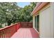 A wooden deck with red railings overlooks lush greenery, accessible through sliding glass doors at 1335 E 3Rd Ave, Mount Dora, FL 32757